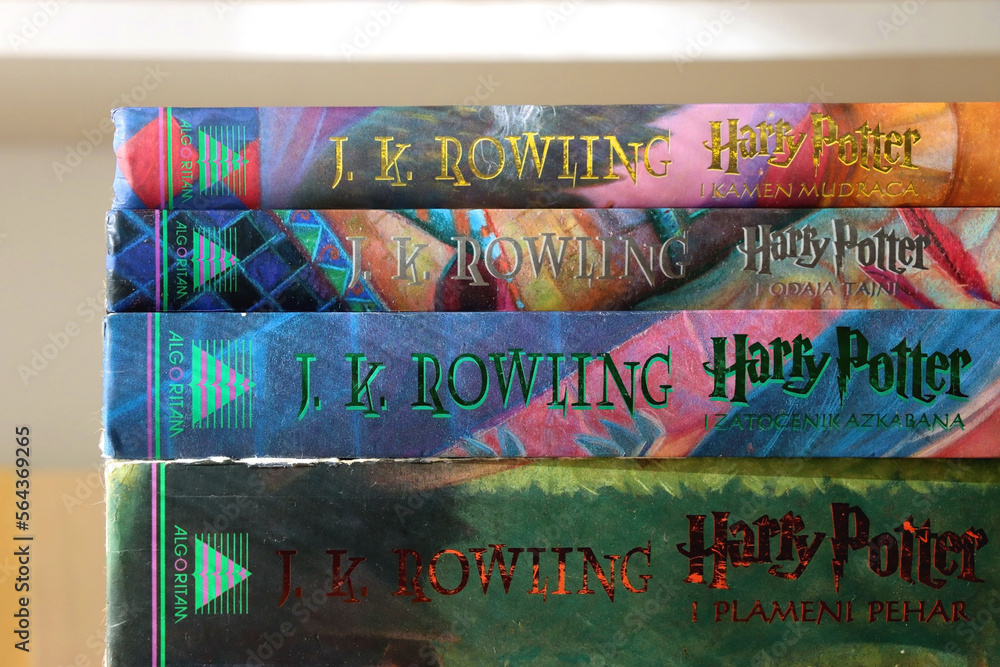 Fototapeta premium Split, Croatia - January 15, 2023: Stack of fantasy books by famous author J. K. Rowling. Bookshelf in the background. Selective focus.