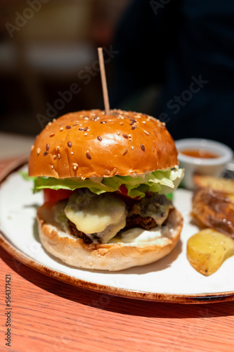 Organic vegetarian burger with plant based falafel balls, vegan cheese, green lettuce and baked potatoes