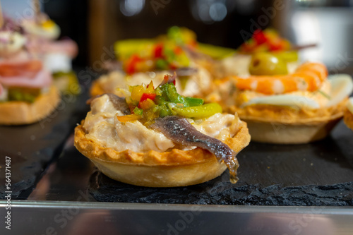 Typical snack of Basque Country, pinchos or pinxtos, small piece of bread with different fish and sea food toppings, served in bar in San-Sebastian or Bilbao, Spain