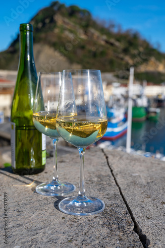 Tasting of txakoli or chacol   slightly sparkling very dry white wine produced in Spanish Basque Country with view on old port and village Getaria  Spain