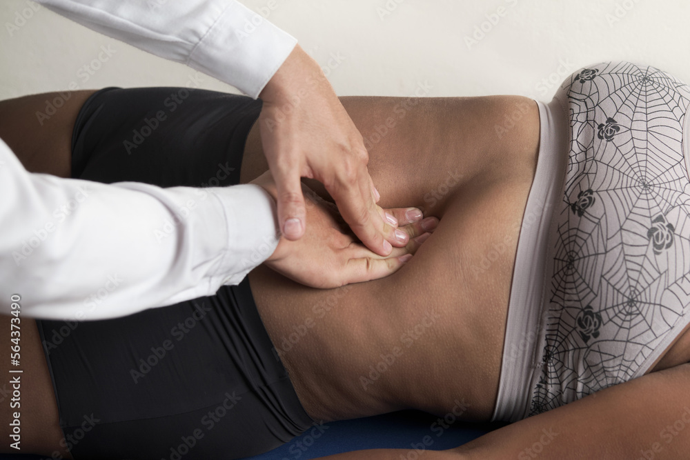 doctor's hands palpating abdomen of unrecognizable African-American woman - obrazy, fototapety, plakaty 