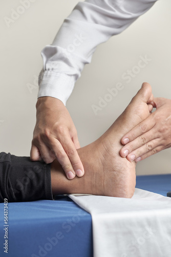 nurse's hand palpating posterior tibial pulse on upright patient's foot photo