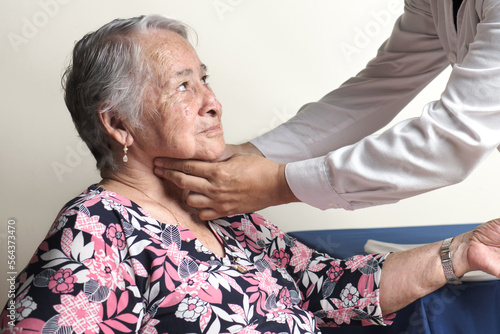 unrecognizable physician palpating carotid pulse of elderly woman photo