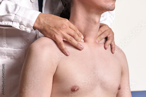 unrecognizable physician palpating subclavian pulse in shirtless male patient