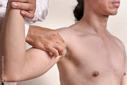 doctor's hands palpating humeral pulse of unrecognizable male patient photo
