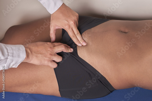 unrecognizable physician's hands palpating femoral pulse in inguinal region of female patient photo