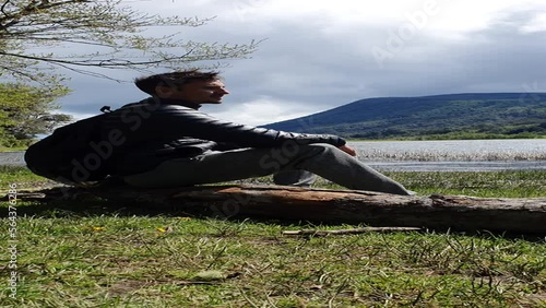 Traveler on a windy day sitting on a log looking at a lagoon in Patagonia