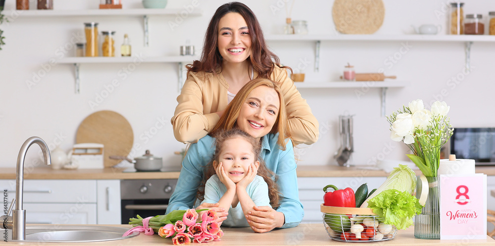 Happy young woman, her little daughter and mother in kitchen at home. International Women's Day celebration Happy young woman, her little daughter and mother in kitchen at home. International Women's Day celebration