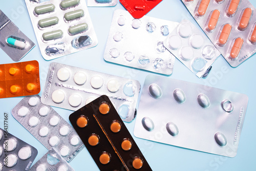 Tablets in blister and pills jar package on blue background.