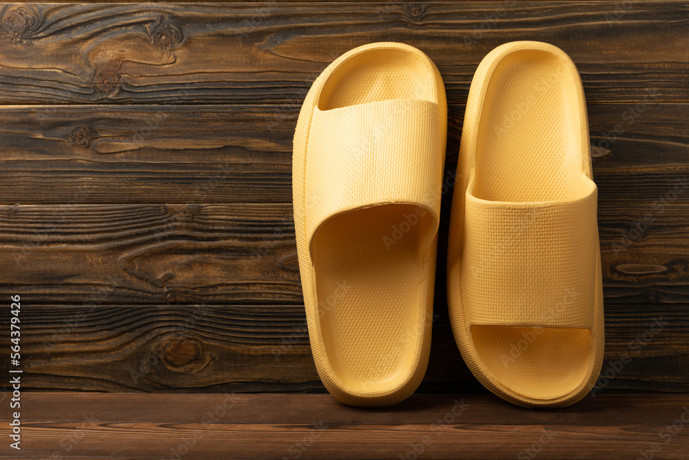 Rubber summer slippers. Replacement shoes for home or office. Yellow slippers on a background of brown space. Relax concepts. Space for text.Space for copy. Rubber summer slippers. Replacement shoes for home or office. Yellow slippers on a background of brown space. Relax concepts. Space for text.Space for copy.