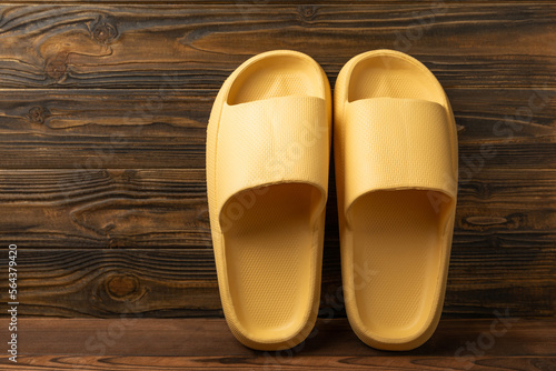 Rubber summer slippers. Replacement shoes for home or office. Yellow slippers on a background of brown space. Relax concepts. Space for text.Space for copy.