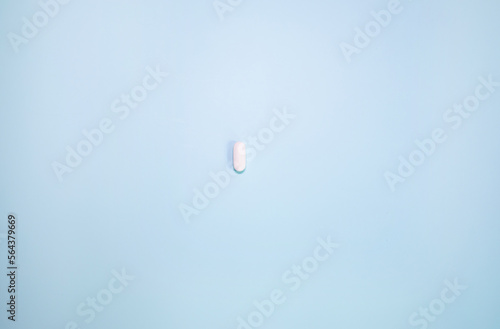 Scattered white pills on blue background.Medical, pharmacy and healthcare concept. Copy space. Empty place for text or logo.