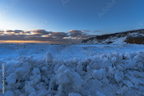 Landscape of the beach area Totally snow covered black sand beach with golden sunrise light under the clouds