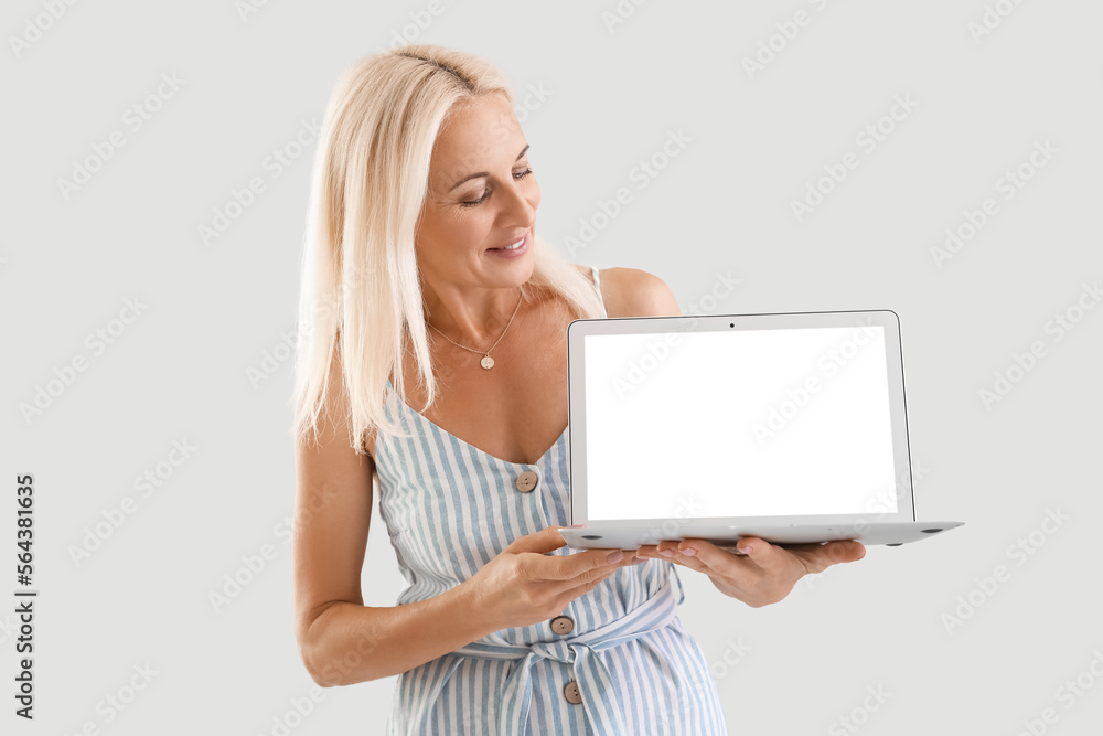 Mature blonde woman with laptop on light background Mature blonde woman with laptop on light background