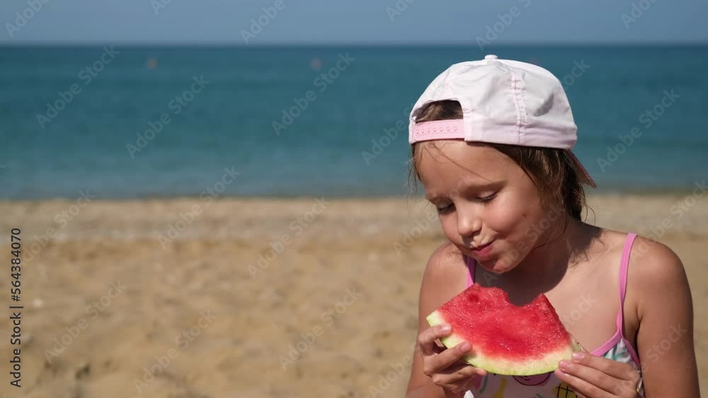 Little girl eats watermelon on the beach. The child eats fruits on the sea with appetite. Little girl eats watermelon on the beach. The child eats fruits on the sea with appetite.