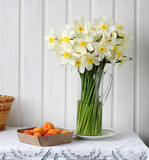 a bouquet of daffodils in a glass jug on the table in the kitchen.