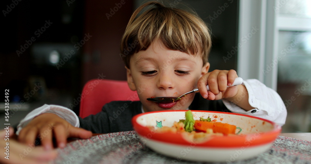 Child eating food by himself kid eats lunch