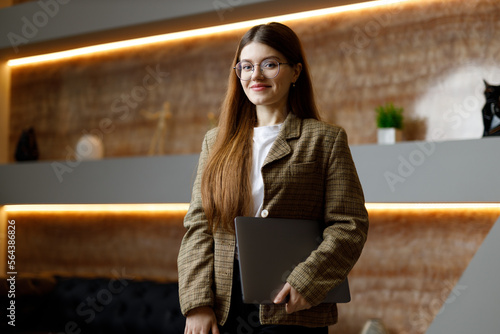 Fotografi Young business assistant, portrait of an attractive girl in a jacket with a laptop