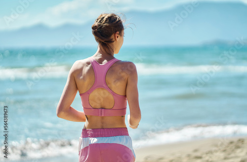 Fototapeta Naklejka Na Ścianę i Meble -  Rear view fit woman in sportswear enjoying nature view at seashore, resting after workout training