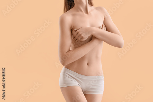Naked young woman on beige background. Breast cancer awareness concept