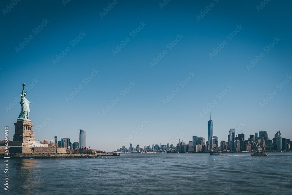 Statue of Liberty in front of NY skyline and blue skies