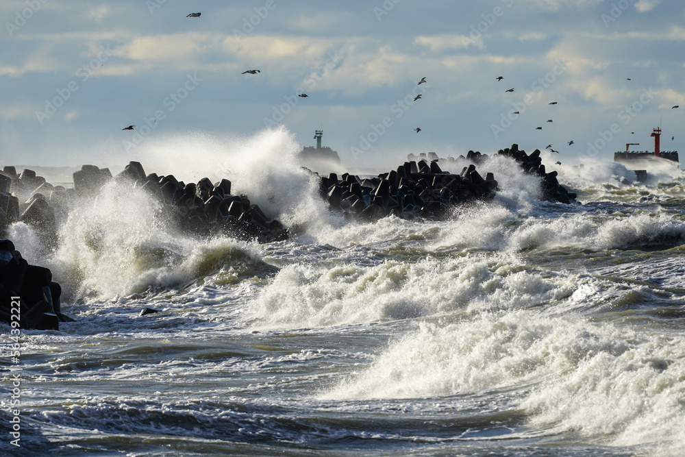 Coastal storm in the Baltic Sea, big waves crash against the harbor breakwater, breaking wave