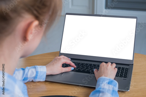 Mock up, copyspace, education, template, entertainment and technology concept. Woman student typing on laptop computer keyboard with white blank screen on wooden table in home interior - mockup image