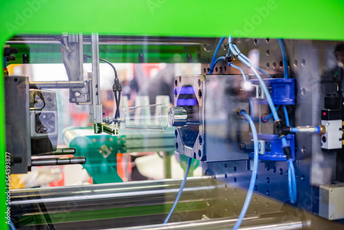 Automatic injection molding machine making disposable plastic cup at exhibition, trade show. Manufacturing, production, technology concept
