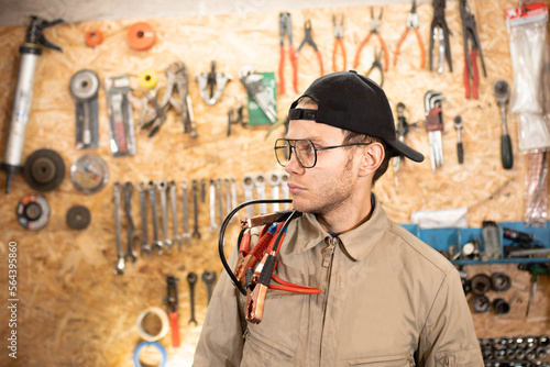 male auto mechanic with wires for charging car battery.