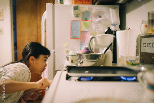Young asian girl baking almond dollar size pancake for her father