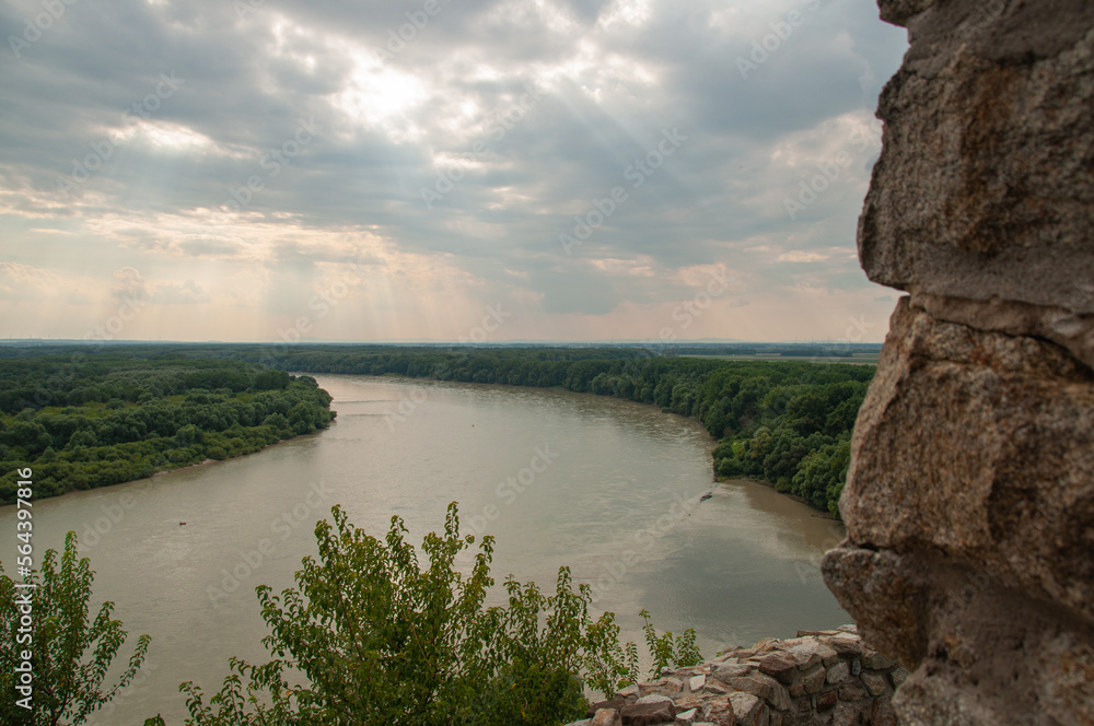 Obraz premium Looking out a window from Devin Castle towards a wide river with sunlight beaming through the clouds in Bratislava, Slovakia