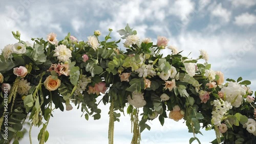 Round arch of fresh flowers on wedding ceremony, aristocratic flowers arch on cloudy sky background, arrangement and decor details for ceremony on royal Villa terrace, exclusive wedding style concept photo