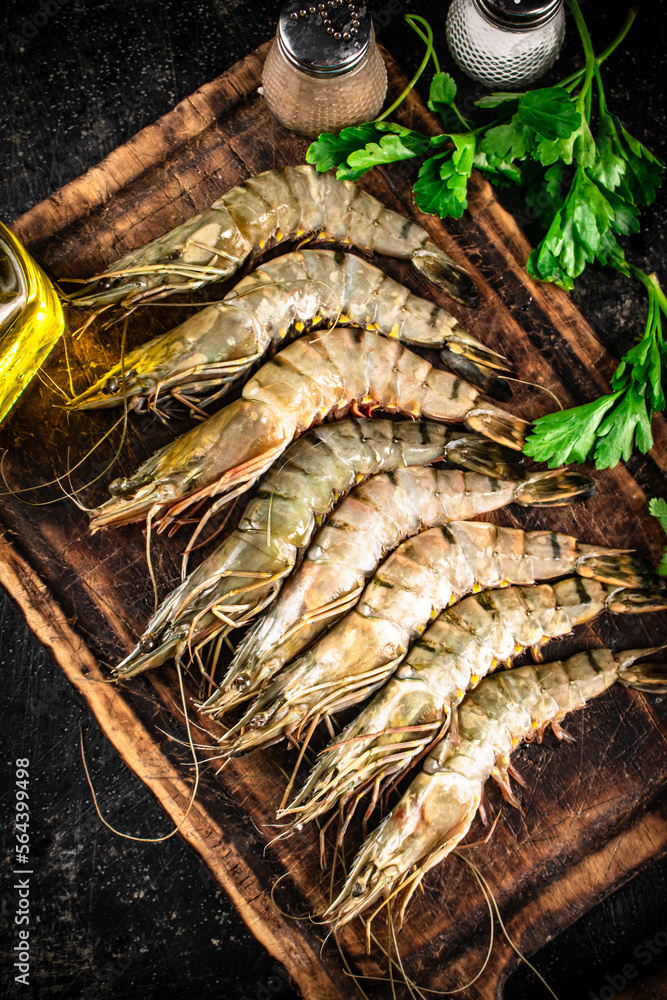 Raw shrimp on a cutting board with spices and parsley. 