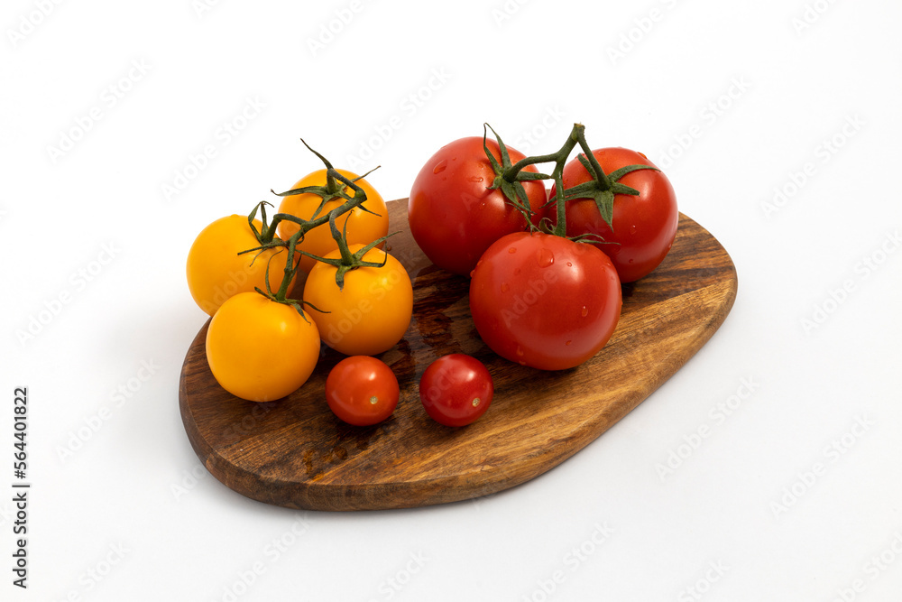 Red and yellow cherry tomatoes on wooden chopping board on white background isolated Red and yellow cherry tomatoes on wooden chopping board on white background isolated