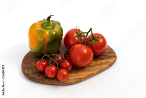 Green pepper and cherry tomatoes on wooden chopping board on white background isolated