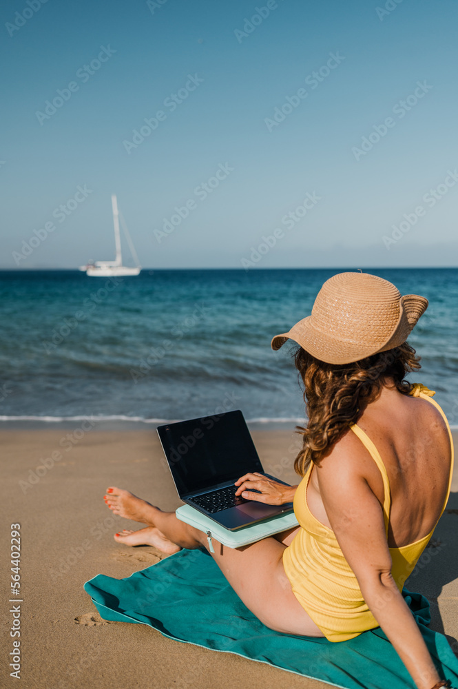 Faceless woman browsing laptop on seashore