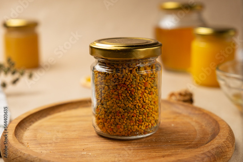Bee pollen in a glass jar with honey in the background