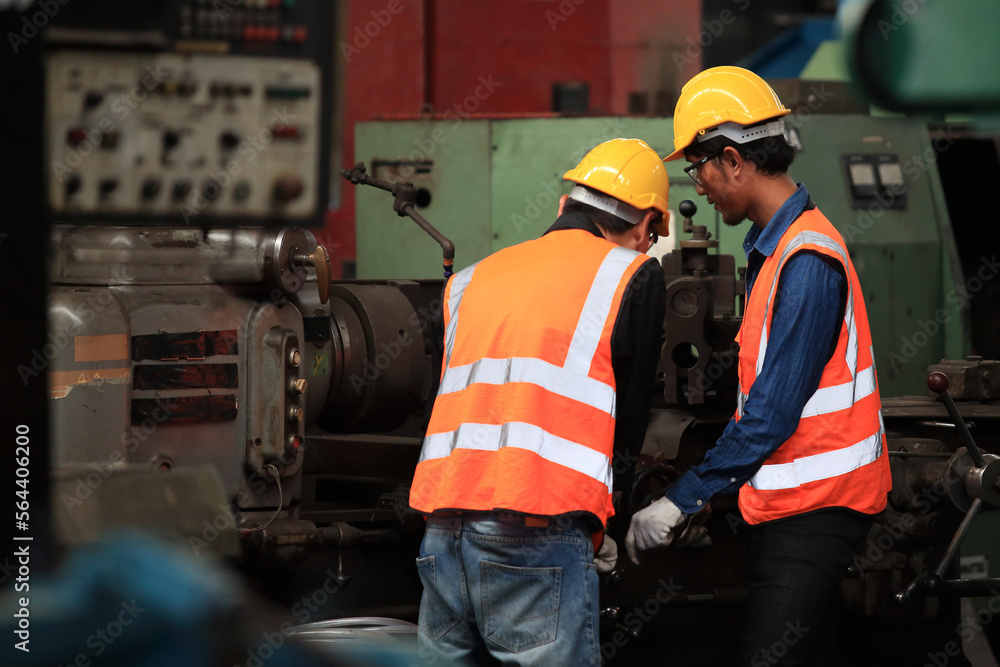 Fototapeta premium Supervisor Consults Young Engineer Working with big machine