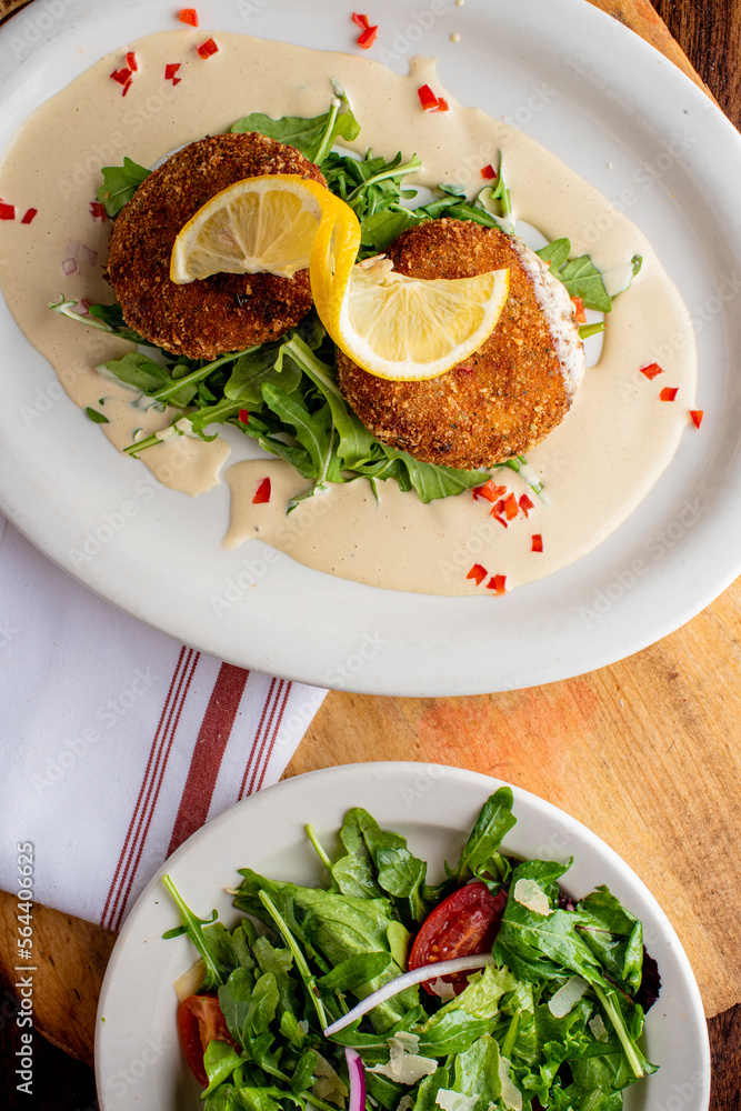 Crab cake. Crab cake served with spicy rémoulade sauce on top of a mixed green salad. Jumbo crab meat mixed with garlic, onions, spices and fried in butter. Classic American restaurant appetizer. Crab cake. Crab cake served with spicy rémoulade sauce on top of a mixed green salad. Jumbo crab meat mixed with garlic, onions, spices and fried in butter. Classic American restaurant appetizer.