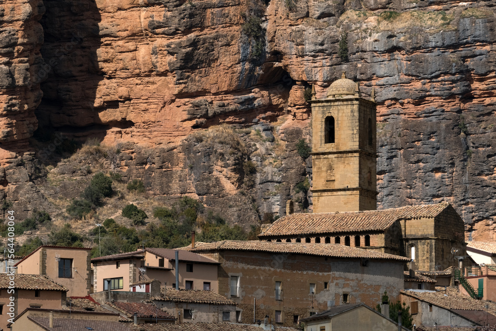 Church of the Agüero village with famous climb walls mountains of Mallos de Agüero (Aguero cliffs) in Huesca in the background.