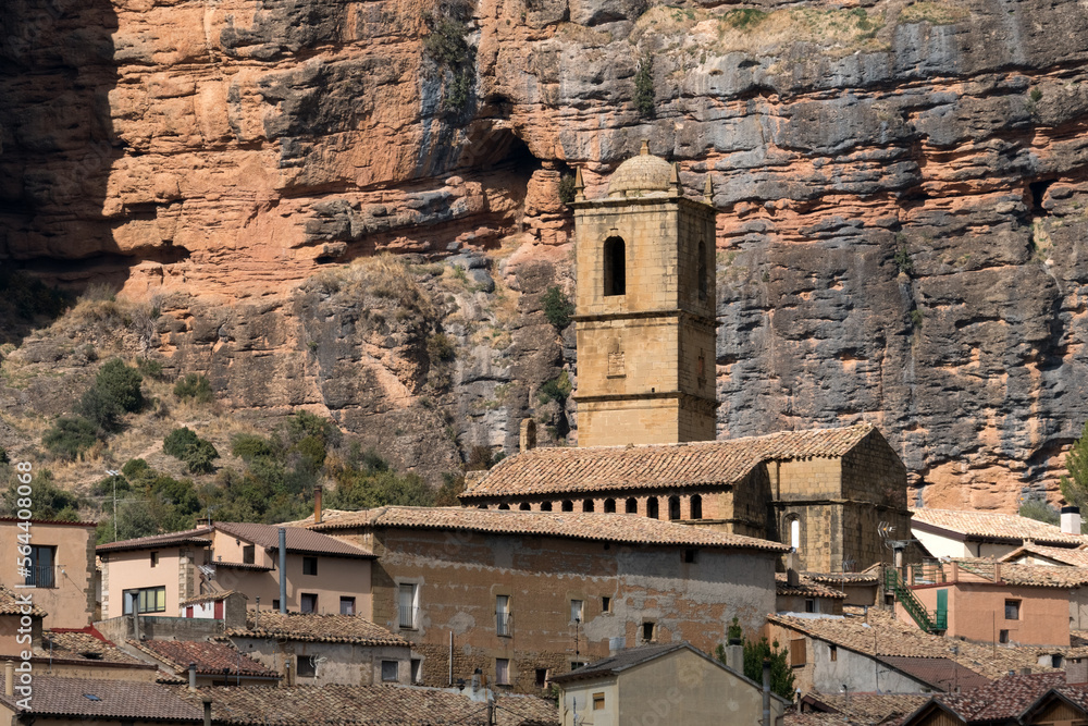 Church of the Agüero village with famous climb walls mountains of Mallos de Agüero (Aguero cliffs) in Huesca in the background.