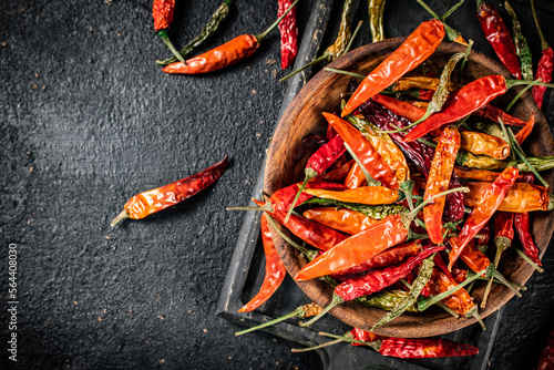 Multicolored pods of dried chili peppers on a cutting board. 