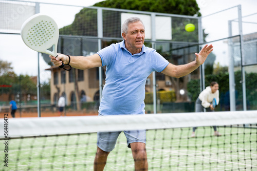 Portrait of emotional aged man enjoying friendly padel tennis match at outdoors court