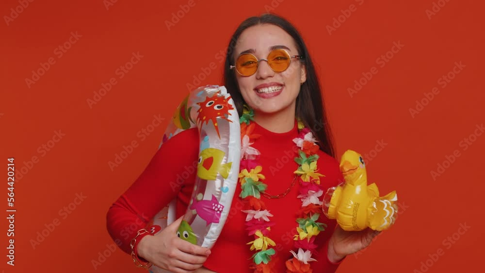 Traveler tourist young woman celebrating, dancing fooling with swimming inflatable duck toy. Concept summer vacation, journey, trip to seaside. Lovely girl in sunglasses on red studio background Traveler tourist young woman celebrating, dancing fooling with swimming inflatable duck toy. Concept summer vacation, journey, trip to seaside. Lovely girl in sunglasses on red studio background