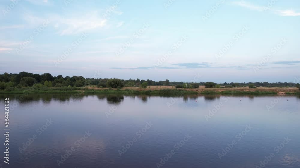 Aerial view of bride and groom hugging on sandy river bank and summer landscape with meadows and trees on other bank Aerial view of bride and groom hugging on sandy river bank and summer landscape with meadows and trees on other bank