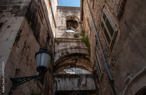 Looking up at an old building alleyway with an arch and street light