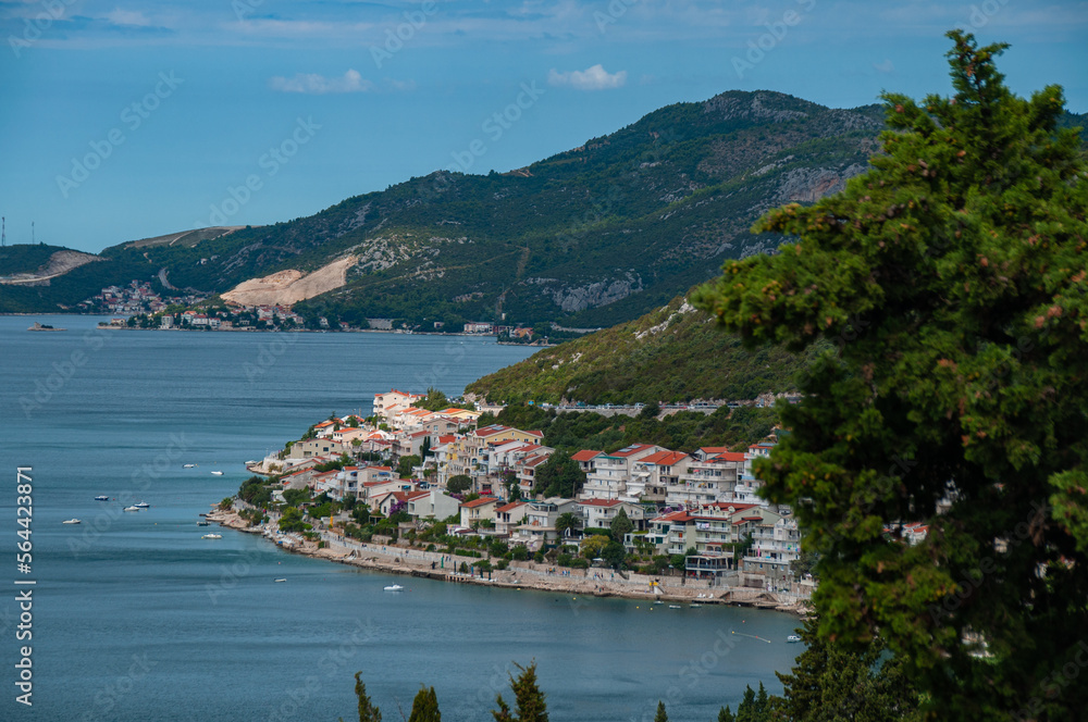 A beautiful bay of water on a sunny day with hills, mountains, trees and houses