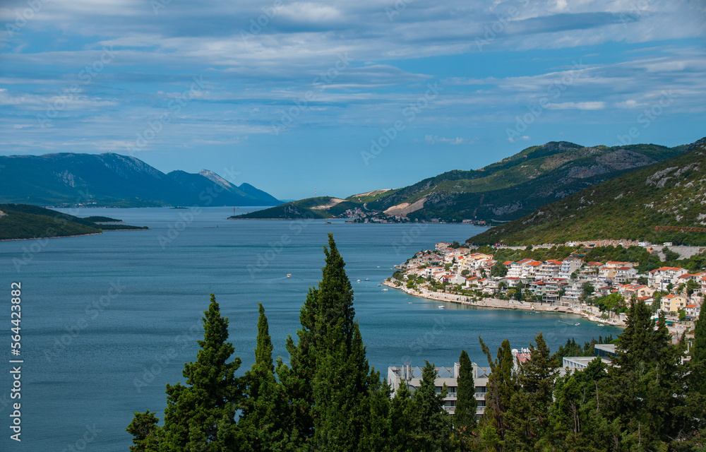 A beautiful bay of water on a sunny day with hills, mountains, trees and houses