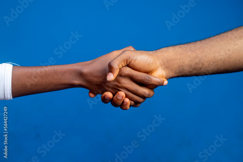 Business agreement handshake over a blue studio background