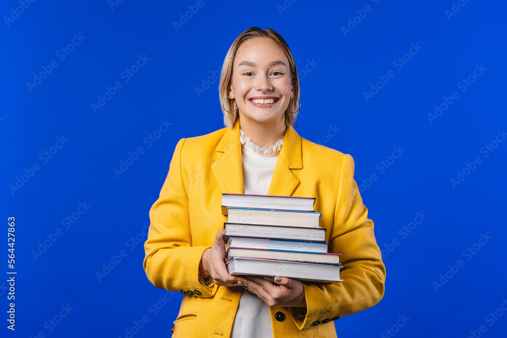 Pensive student woman with stack of books from library on blue. Copy space. Pensive student woman with stack of books from library on blue. Copy space.
